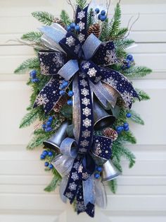 a blue and silver christmas wreath with pine cones, bells and snowflakes on it