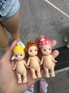 a person holding five little dolls in their hand on the ground with other small toy figures behind them