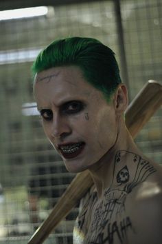 a man with green hair and makeup holding a baseball bat in front of his face