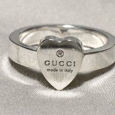 Crafted From 925 Sterling Silver, This Timeless Piece Features A Heart Detail That Defines The Love Ring. Reflecting Gucci's Romantic Narrative, The Ring Is Further Enhanced By The Gucci Trademark. This Luxury Accessory Is Perfect For Any Occasion, Blending Elegance & Style! : Stunning 925 Sterling Silver Width: 0.15" Inch () Women’s Us Size: 6 Made In Italy This Ring Embodies Gucci’s Commitment To Social & Environmental Responsibility, Ensuring Sustainable Craftsmanship. Bundle With Another Ite Modern Sterling Silver Heart Ring For Gift, Modern Sterling Silver Heart Ring Gift, Gucci White Gold Jewelry For Anniversary, Modern Sterling Silver Jewelry For Valentine's Day, Luxury Engraved Silver Ring With Hallmarks, Gucci White Gold Ring In Fine Jewelry Style, Gucci Fine Jewelry White Gold Rings, Designer Gucci Rings With Polished Finish, Gucci White Gold Fine Jewelry Ring