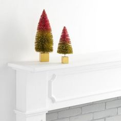 two small trees sitting on top of a white mantle