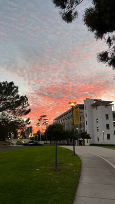 the sky is pink and blue as it sets over a building in an area with green grass