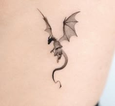 a small dragon tattoo on the back of a woman's shoulder