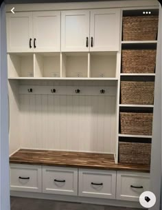 a room with white cabinets and baskets on the wall