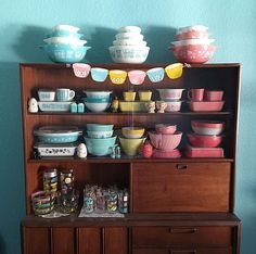 an old wooden cabinet with bowls and cups on it