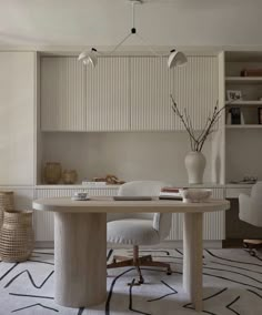 a table with chairs and a vase on it in front of a bookshelf