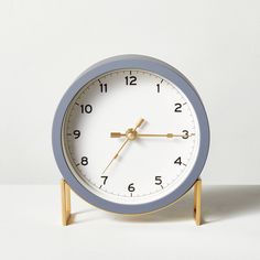 an alarm clock sitting on top of a wooden stand in front of a white wall