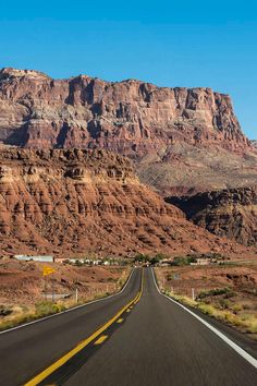 an empty road in the desert with mountains in the background