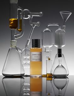 an assortment of glass flasks and beakles with liquid in them on a reflective surface