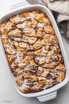 a casserole dish filled with cinnamon rolls covered in icing and drizzle