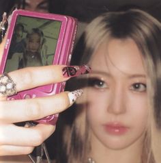 a woman holding up a pink cell phone