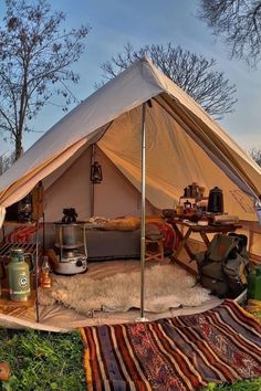 a tent is set up in the grass with blankets and other items on top of it