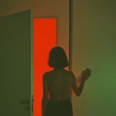 a woman standing in front of a red door with her hands out to the side