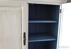 a white cupboard with blue shelves in the corner and an open door on one side