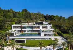 an aerial view of a house surrounded by palm trees and greenery in the foreground