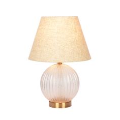 a white glass lamp with a gold base and a beige linen shade on the top