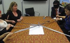 four people sitting around a table with scissors in the shape of a plane on it