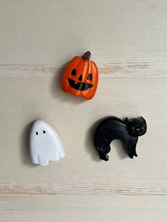 three halloween decorations on a table with one black cat and the other white ghost face