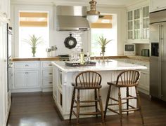 a kitchen with two stools at the center of the island and an oven in the back