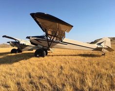 a small plane parked on top of a dry grass field