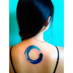 the back of a woman's shoulder with a blue circle tattoo on it