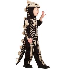 a little boy in a skeleton costume is walking with his hand out to the side