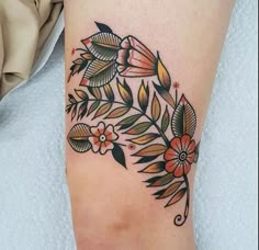 a woman's leg with flowers and leaves tattoo on the side of her thigh