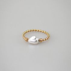 The beautiful ring features a unique half-pearl and half-gold design. The tiny pearls are baroque pearls with irregular, undulating shape and creamy white hue, strung together by a rubber band. While the gold band is crafted from gold plated stainless steel for a luxurious, eye-catching look. This ring will add a touch White Pearl Ring With Pearl Chain, White Pearl Charm Ring Jewelry, Gold Pearl Ring With Charm For Gift, White Pearl Charm Ring, Elegant Gold Rings With Baroque Pearls, Pearl Chain Ring Jewelry, Elegant Gold Pearl Ring With Baroque Pearl, Gold Baroque Pearl Ring For Wedding, Elegant Gold Baroque Pearl Ring