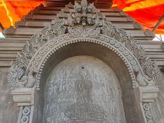 an intricately carved doorway with orange and yellow flags in the backgrouds