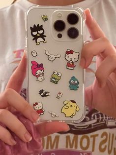 someone holding up their phone case with hello kitty stickers on it