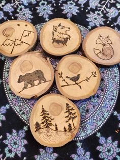 four wooden coasters with animals on them sitting on a blue and purple floral cloth