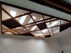 an unfinished ceiling with wooden slats in the center and skylights above it on either side