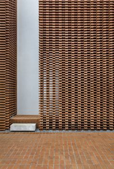 an outdoor area with brick flooring and walls made out of wooden slatted panels