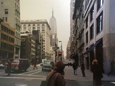 people are walking down the street in an old city with tall buildings and skyscrapers