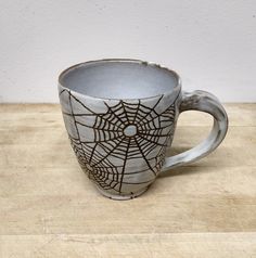 a spider web mug sitting on top of a wooden table