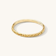 a yellow gold ring with an intricate design on the inside and outside, set against a white background