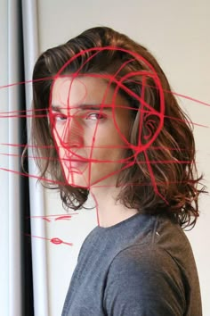 a young man with long hair is looking at something in front of him and has red lines over his face