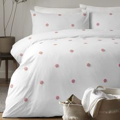 a bed with white sheets and pink polka dots on the comforter is shown in this image