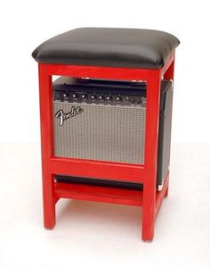 a red and black stool with an amp on it's back side, against a white background