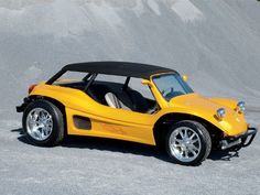 a yellow sports car parked in front of a sand dune area with its doors open