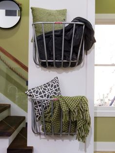 two metal baskets are hanging on the wall next to some pillows and throw pillows in front of a window