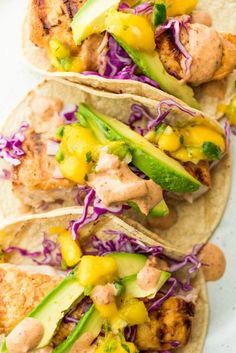 three tacos with chicken, lettuce and pineapple slaw on them