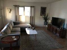 a living room filled with furniture and a flat screen tv on top of a wooden table