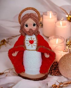 a crocheted nativity doll next to candles and other holiday decorations on a bed