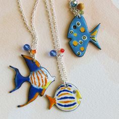 three necklaces with different colored fish on them