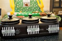 three kettles sitting on top of a counter in front of a football themed wall