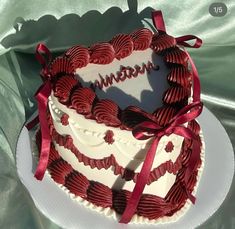 a heart shaped cake with red ribbon and name written on the top, sitting on a white plate