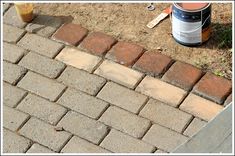 a brick walkway being laid next to a can of paint