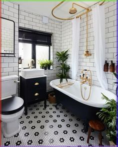 a bathroom with black and white tile, gold fixtures and plants in the bathtub