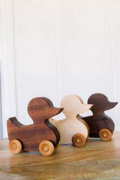 three wooden ducks sitting on top of a table